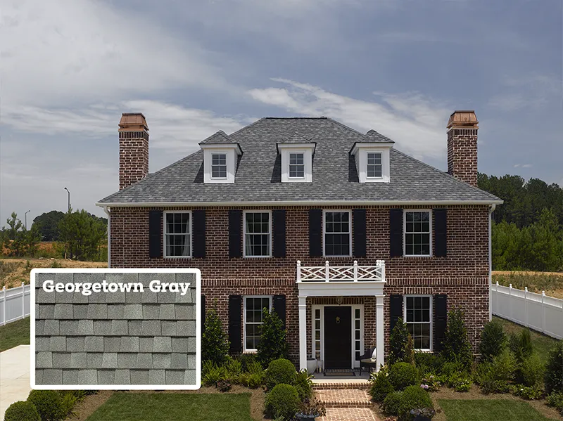 picture of a brick multistory home with white trim and georgetown grey shingles