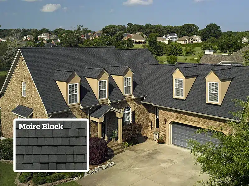 aerial shot of a tan colored brick house with moire black shingles