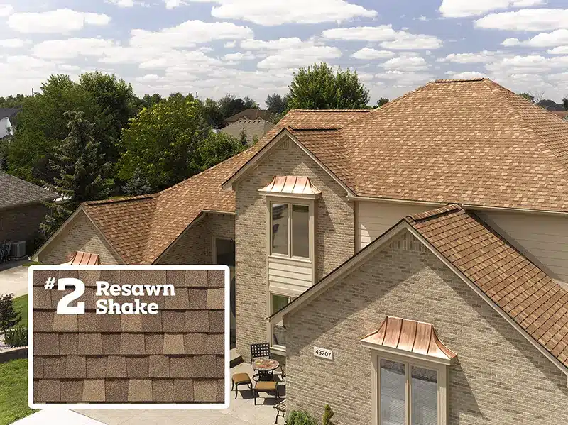 aerial shot of a tan colored brick house with moire black shingles