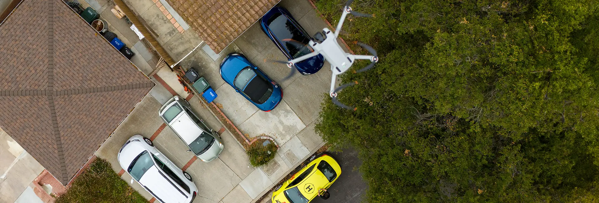 LocalRoofs drone flying over a house, inspecting the roof. LocalRoofs car and salesperson in the distance on the ground