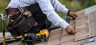 Closeup of a roofer laying shingles down