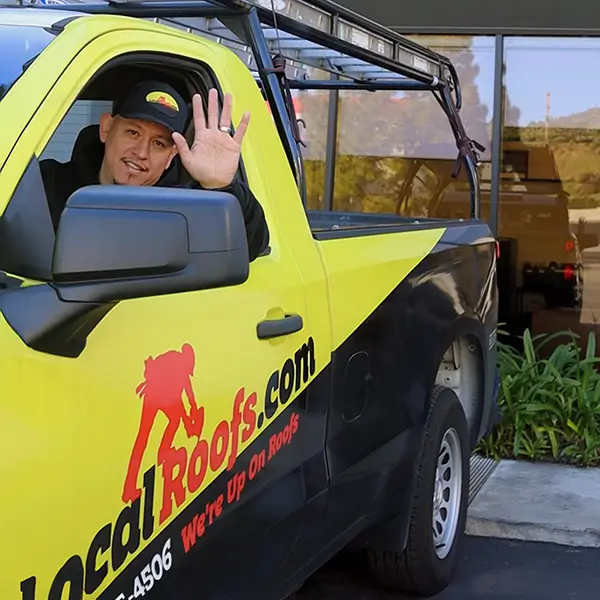 LocalRoofs team member waving and driving a LocalRoofs truck